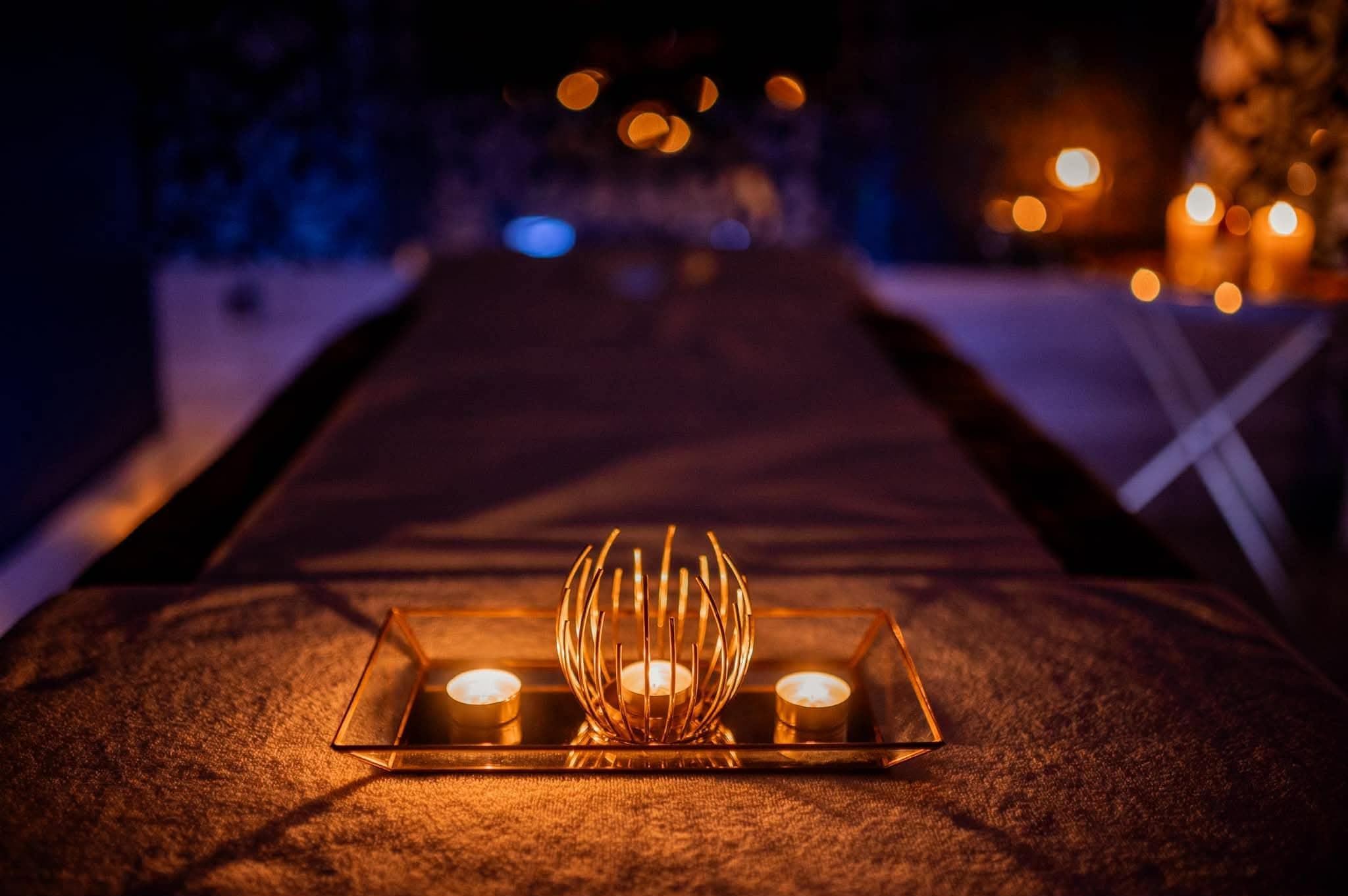 Ciepłe światło świec na leżance do masażu w gabinecie Namaste Massage Studio